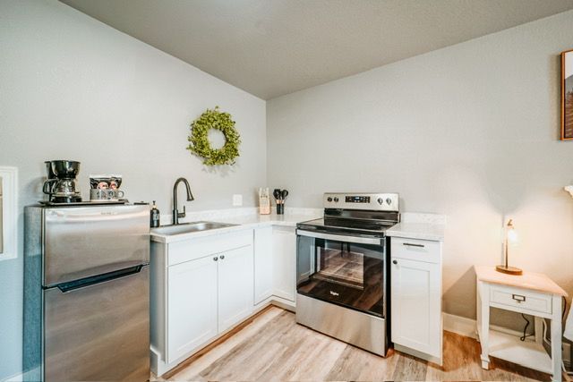 Bright white kitchen with stainless steel appliances, small wreath, and a side table lamp