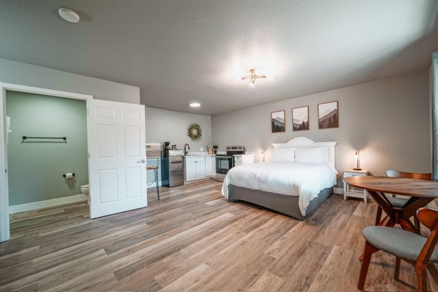 Spacious bedroom with a bed, desk, dresser, and gray walls, viewed from the doorway