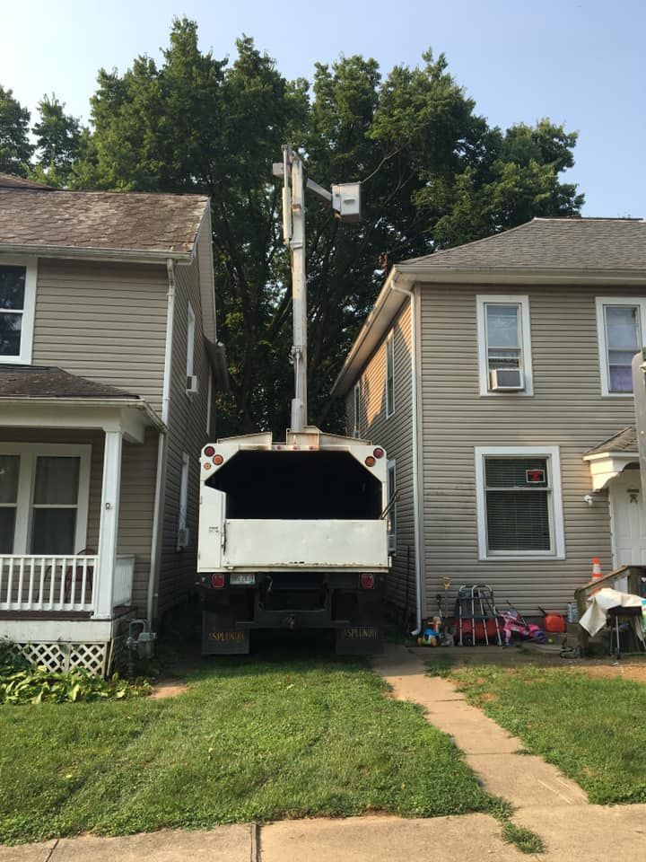 Truck with elevated lift between two houses on a grassy driveway.