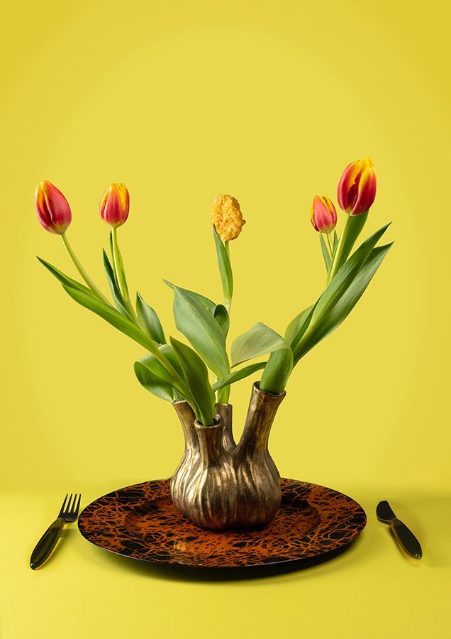 Een vaas gevuld met bloemen staat op een bord