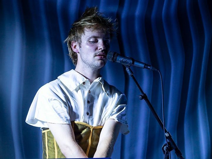 Een man zingt in een microfoon naast een Apple-laptop