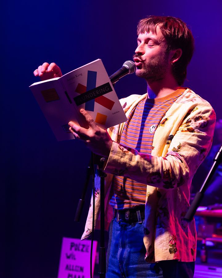 Een man die in een microfoon zingt voor een bord waarop staat 'prijs'