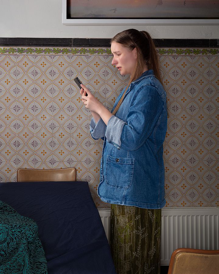 Een vrouw in een spijkerjasje kijkt naar haar telefoon