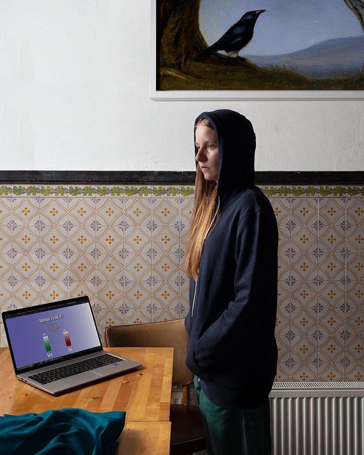 Een meisje in een hoodie staat voor een laptop