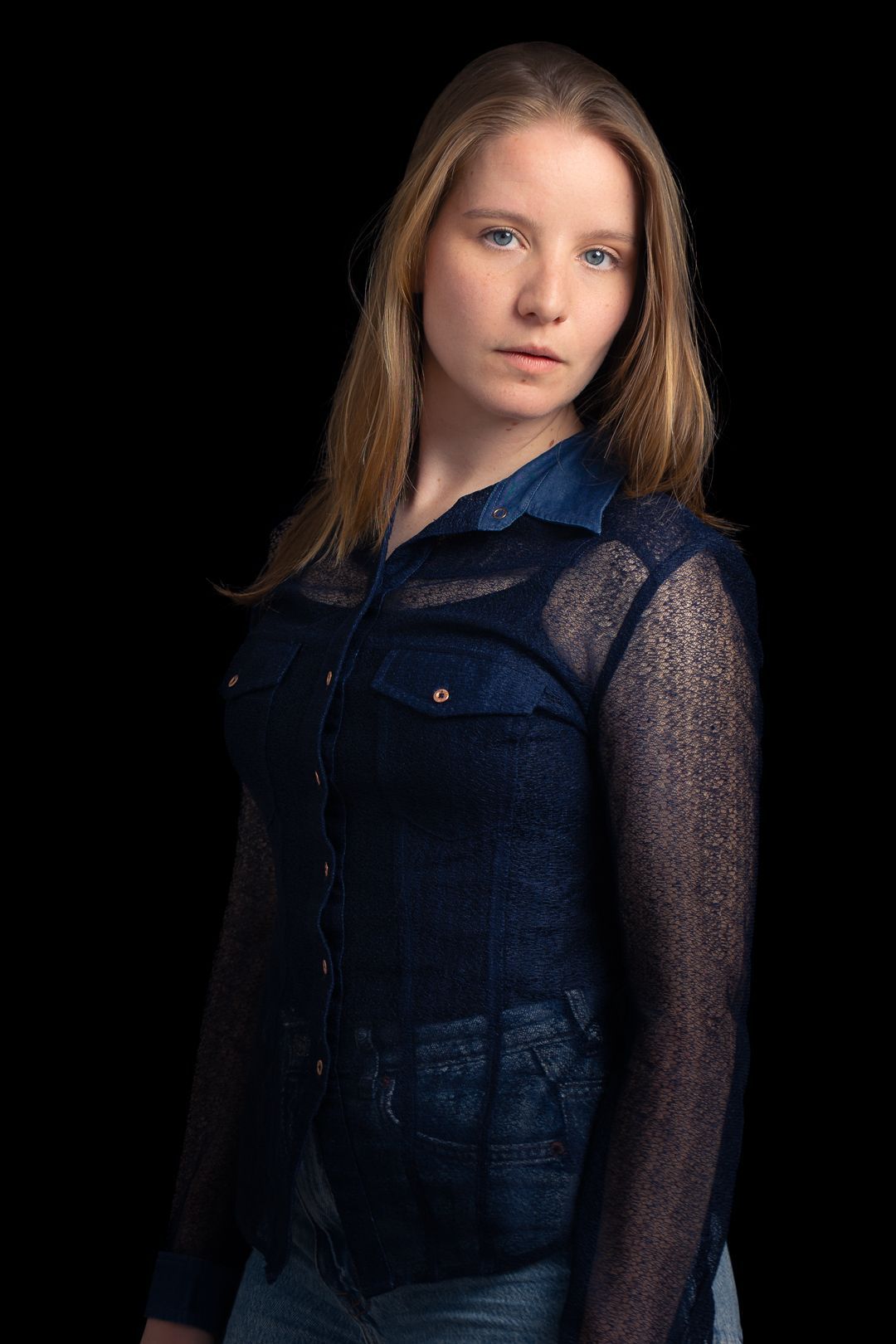 Een vrouw in een blauw shirt staat voor een zwarte achtergrond