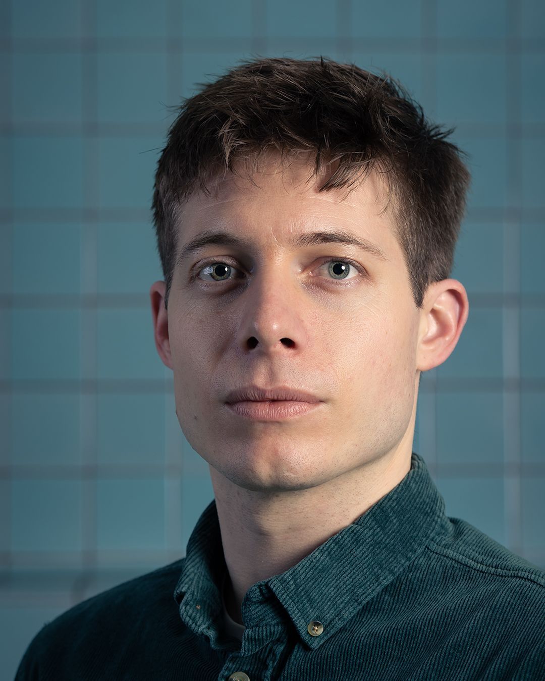Een jongeman in een groen shirt kijkt naar de camera