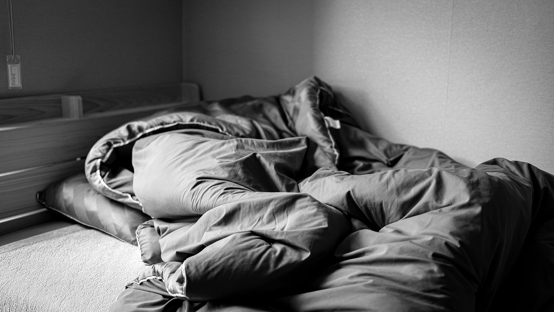 Een zwart-witfoto van een bed bedekt met dekens en kussens.