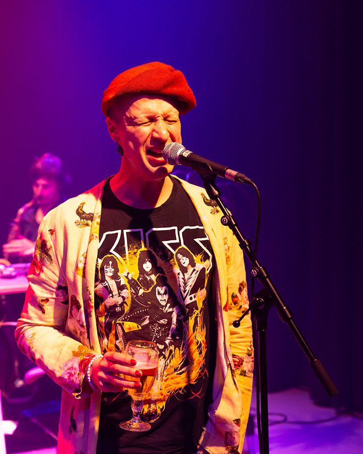 Een man met een rode hoed zingt in een microfoon