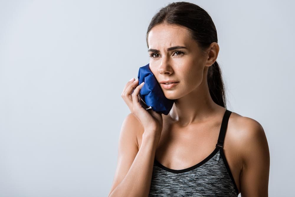 A woman is holding an ice pack to her face.