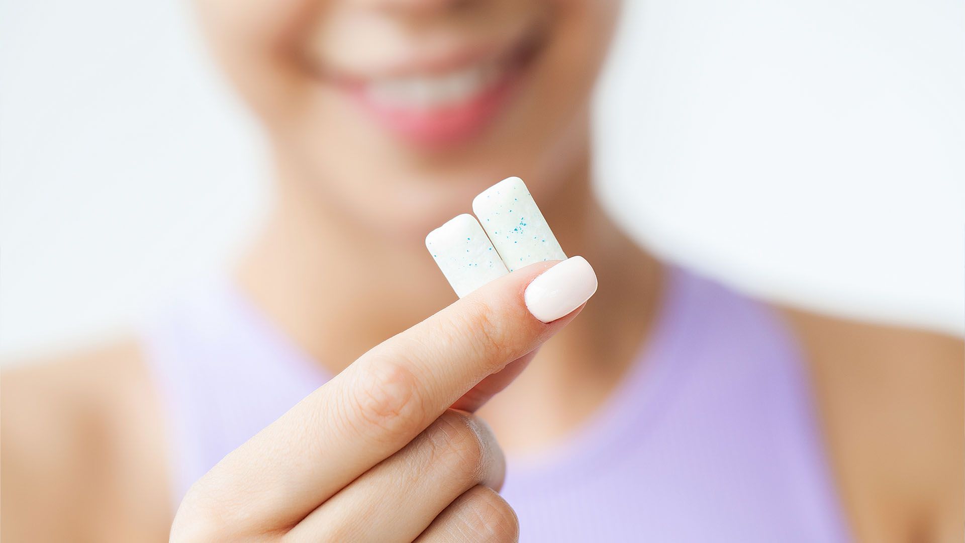 Person holding two mint-colored pieces of chewing gum between their finger