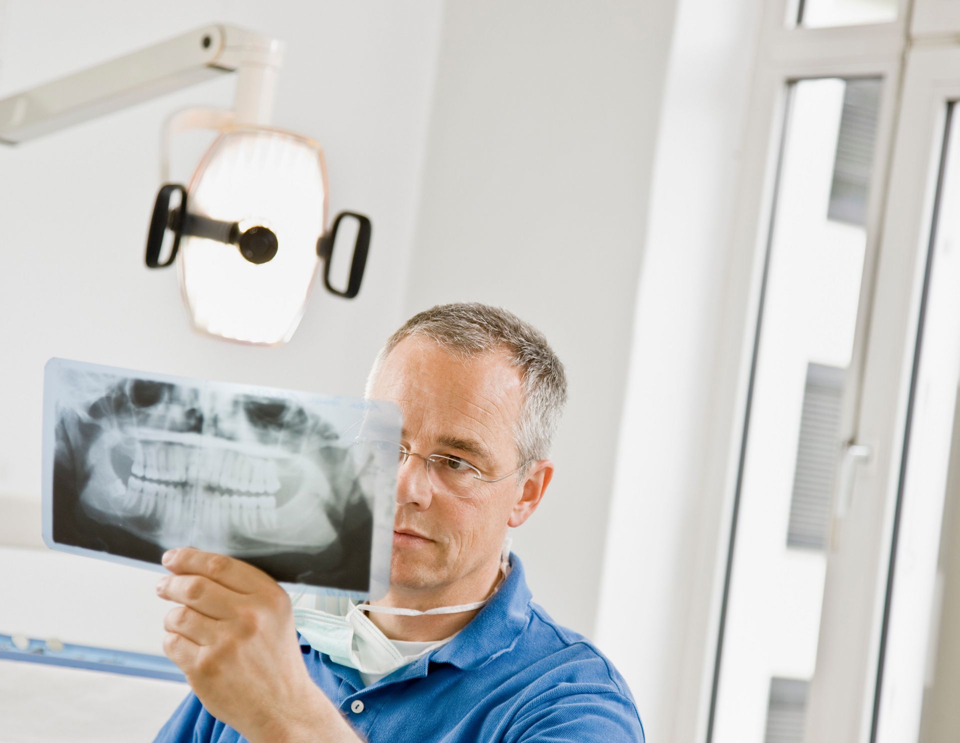 Dentist examining a panoramic dental X-ray in a bright clinic room
