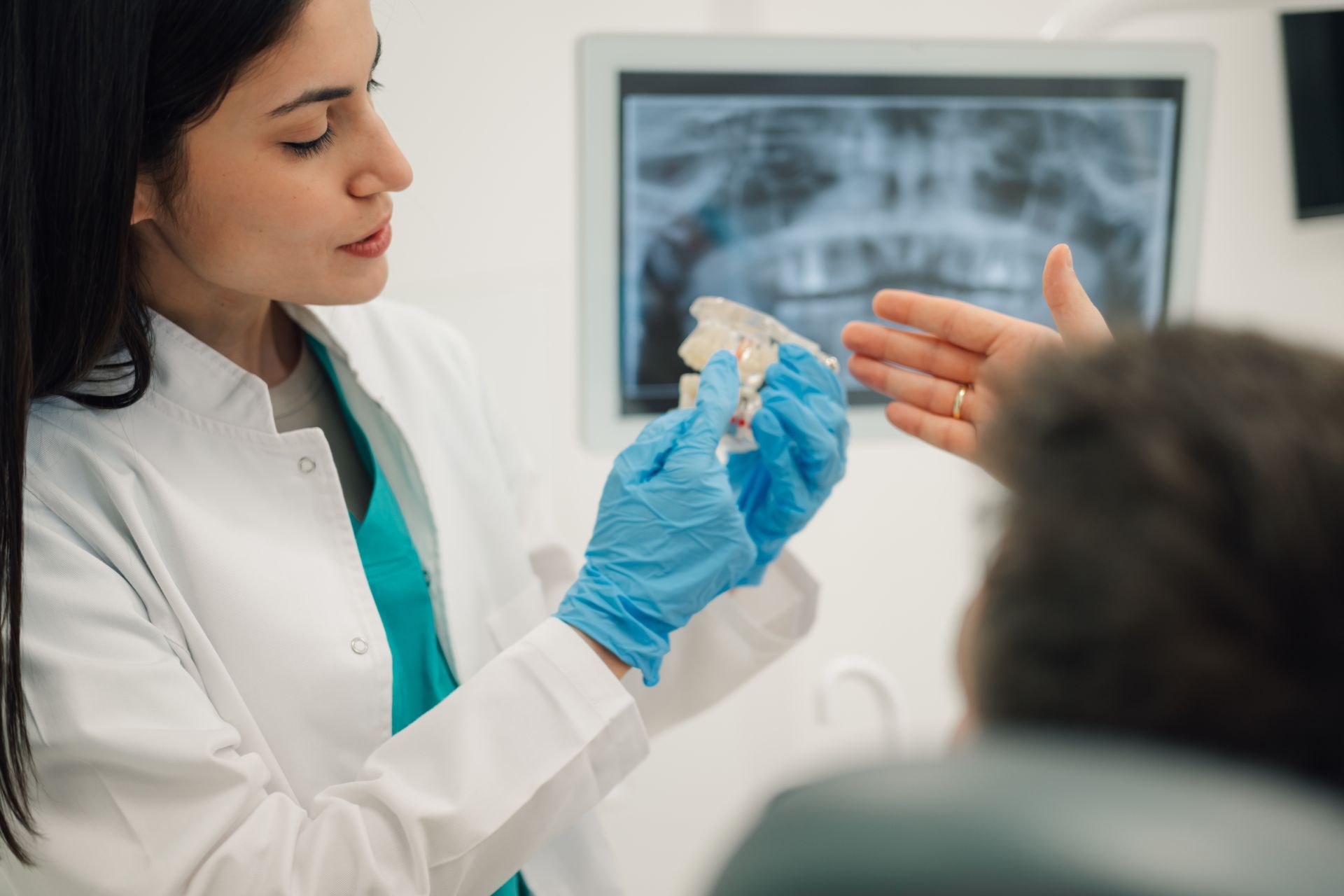 Dentist showing a dental mold to a patient in a bright clinic office