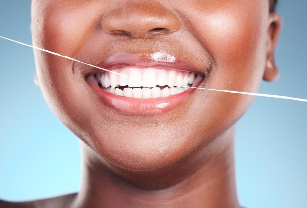 A woman is flossing her teeth with dental floss.