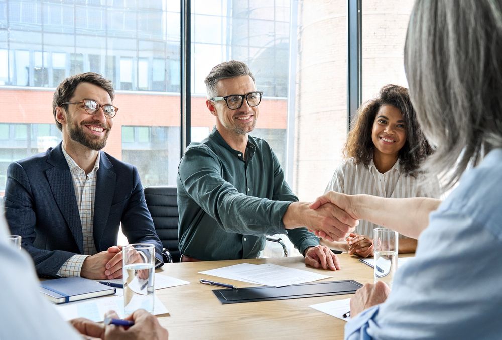 Business Meeting With People Shaking Hands at a Table — People Assured Partners in Mackay, QLD