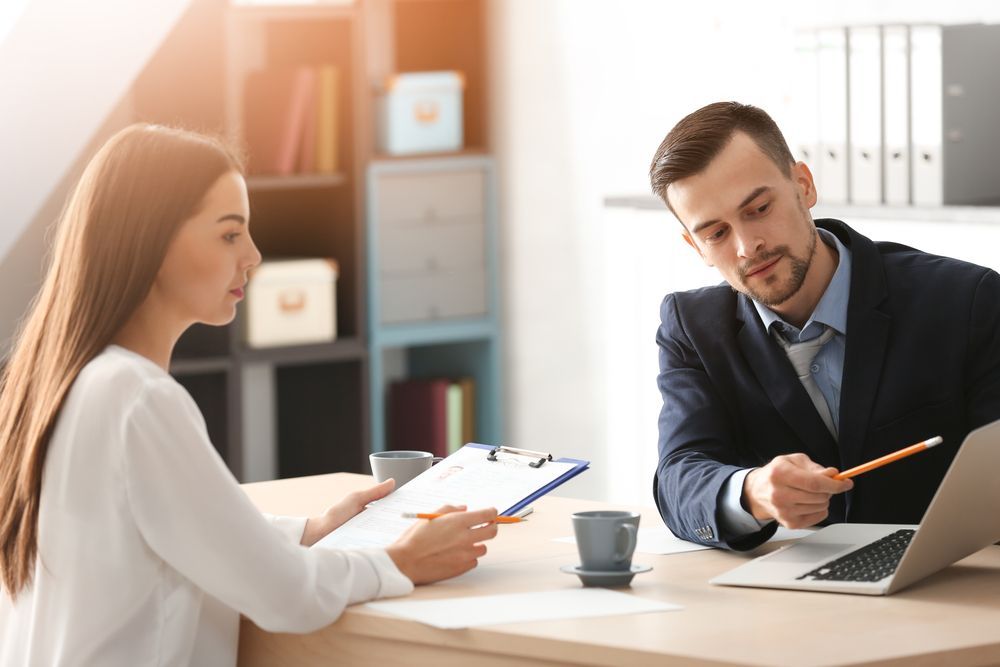 Woman and Man in an Office Setting, Reviewing Documents — People Assured Partners in Cairns, QLD