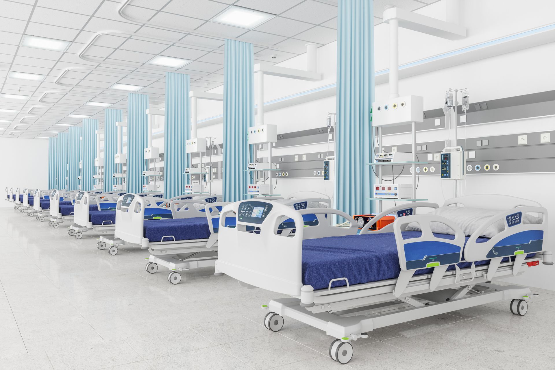 A row of hospital beds are lined up in a hospital room.