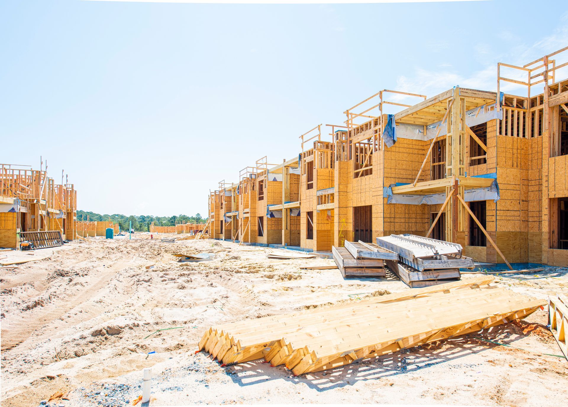 A row of wooden houses are being built on a construction site.