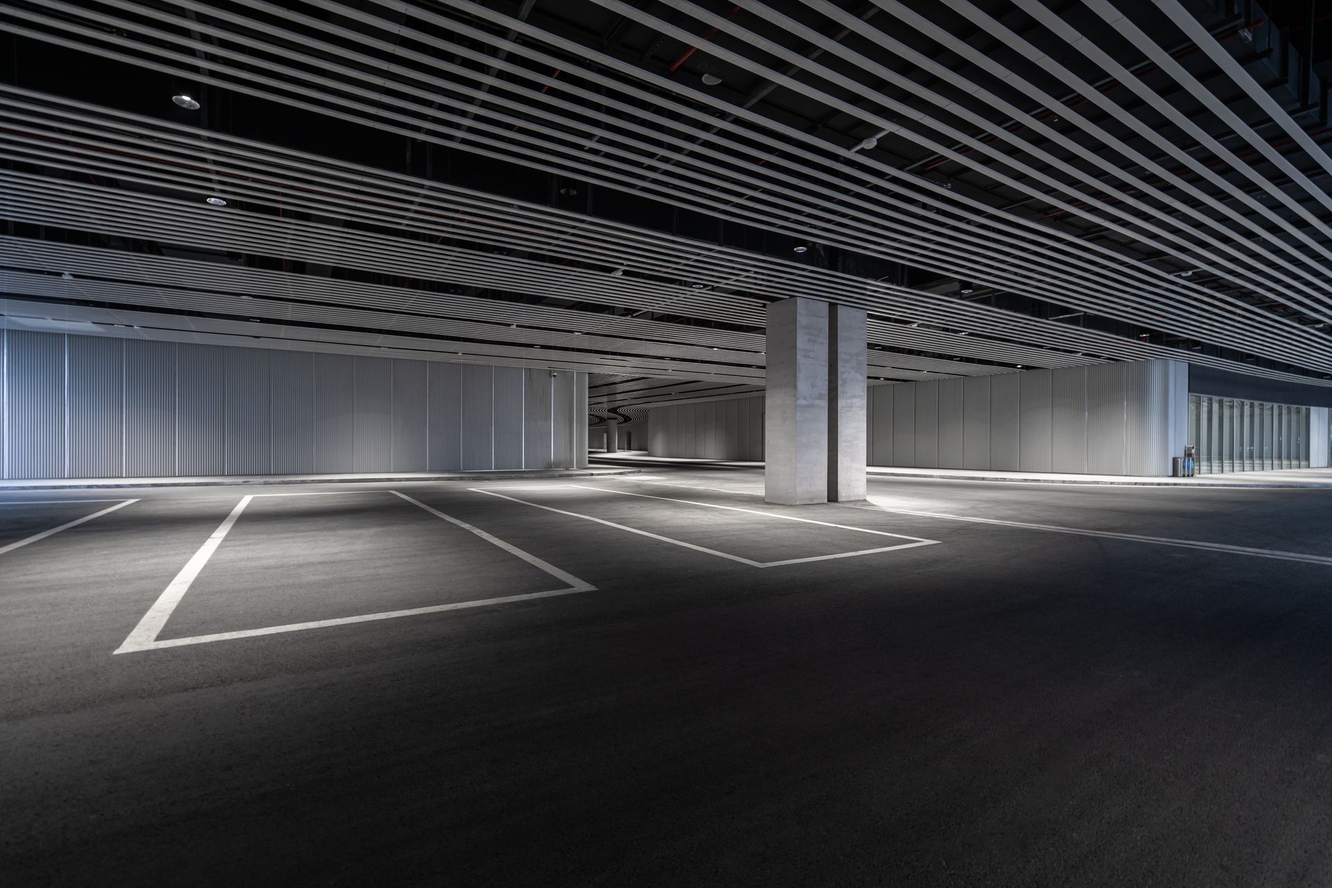 An empty parking garage with a striped ceiling and a handicapped parking spot.