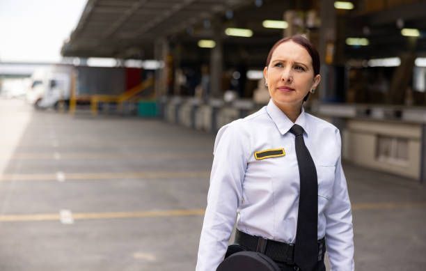 A woman in a white shirt and black tie is standing in a parking lot.