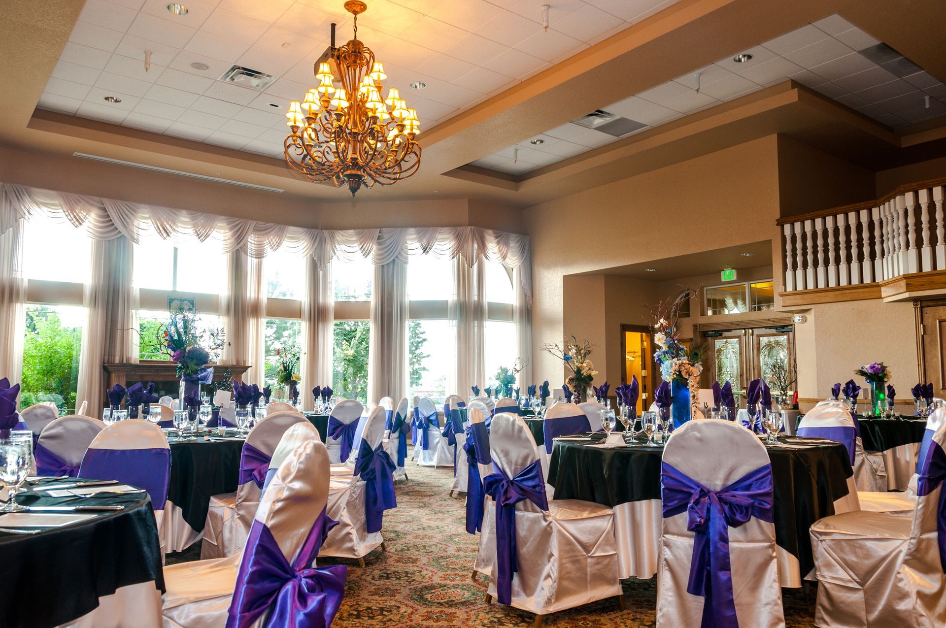 A large room with tables and chairs set up for a wedding reception