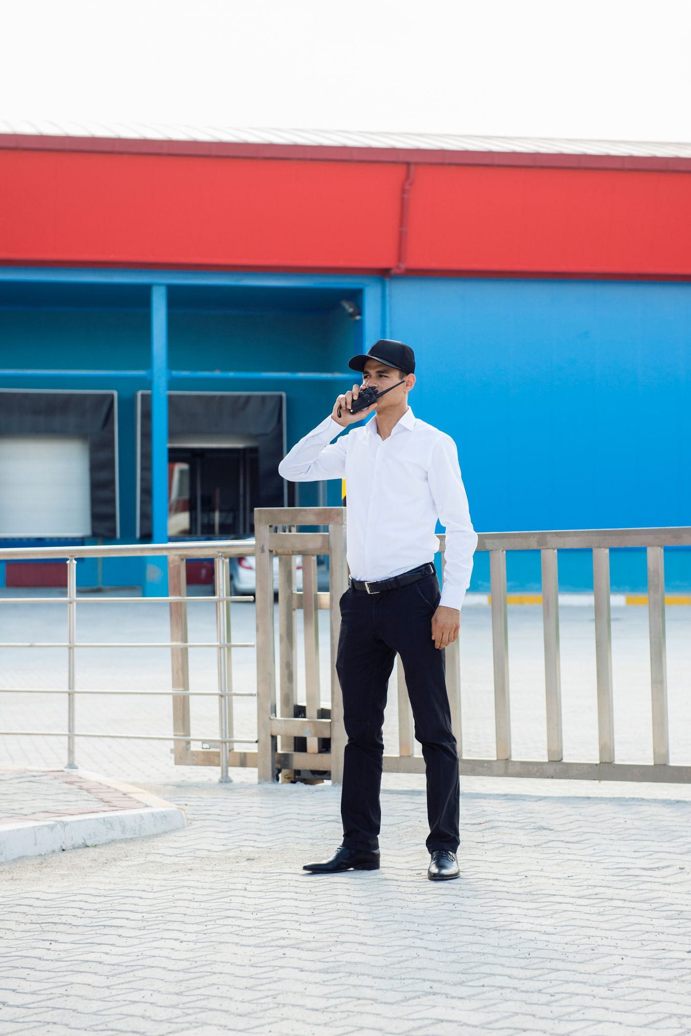 A man is standing in front of a building talking on a cell phone.