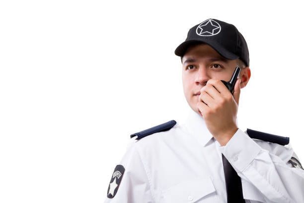 A security guard is talking on a walkie talkie.