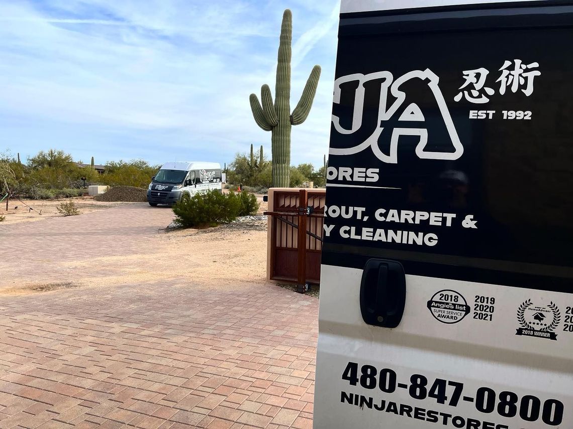 A ninja cleaners van is parked next to a cactus