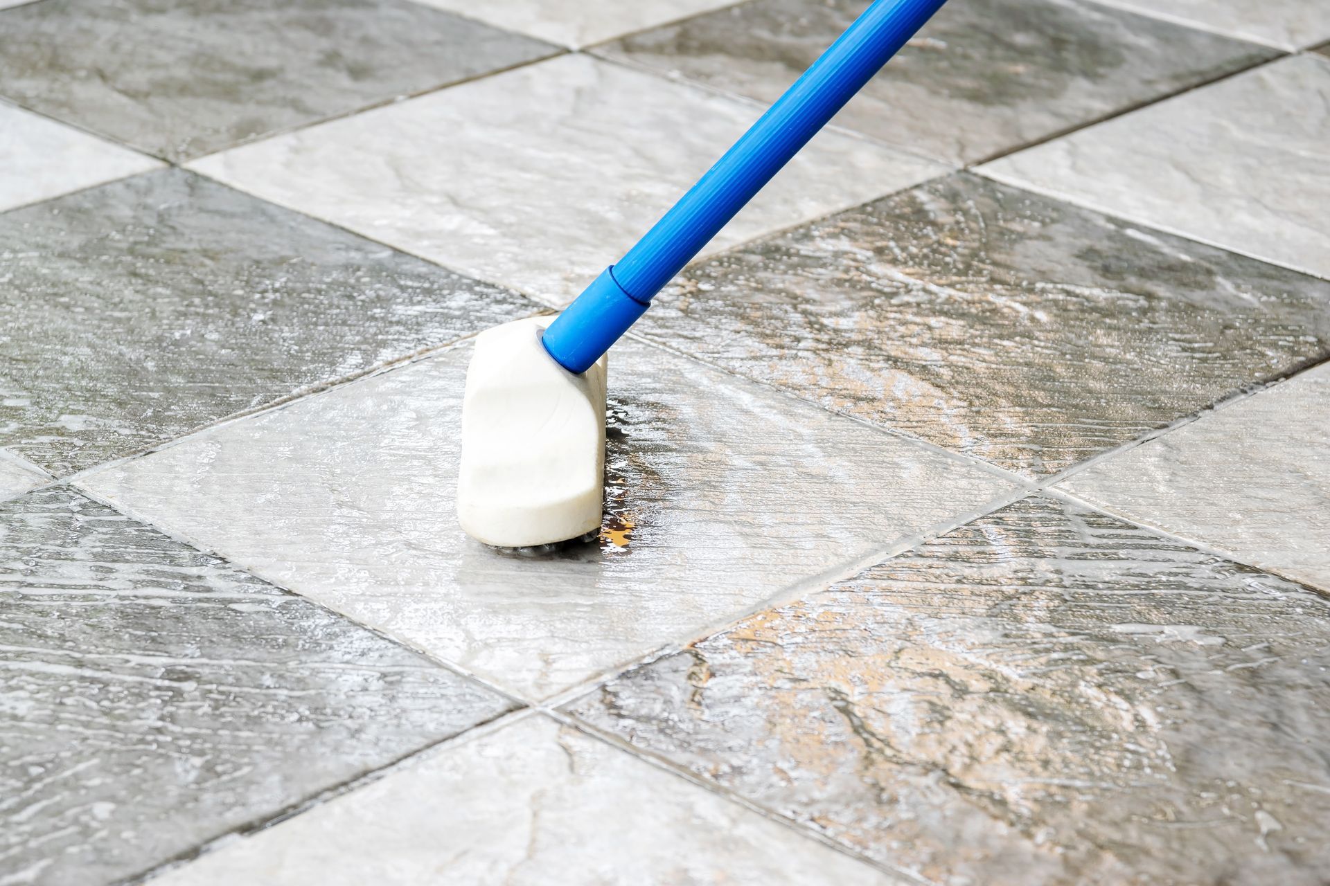 A person is cleaning a tiled floor with a mop.