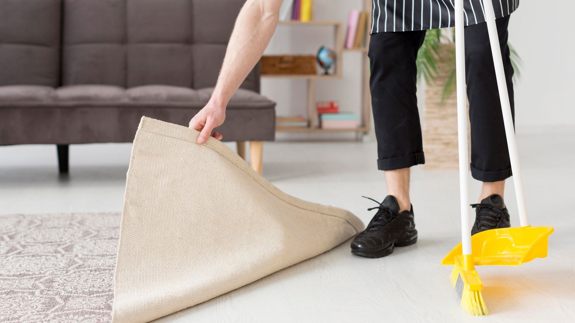 A woman is cleaning the floor with a broom and a rug.