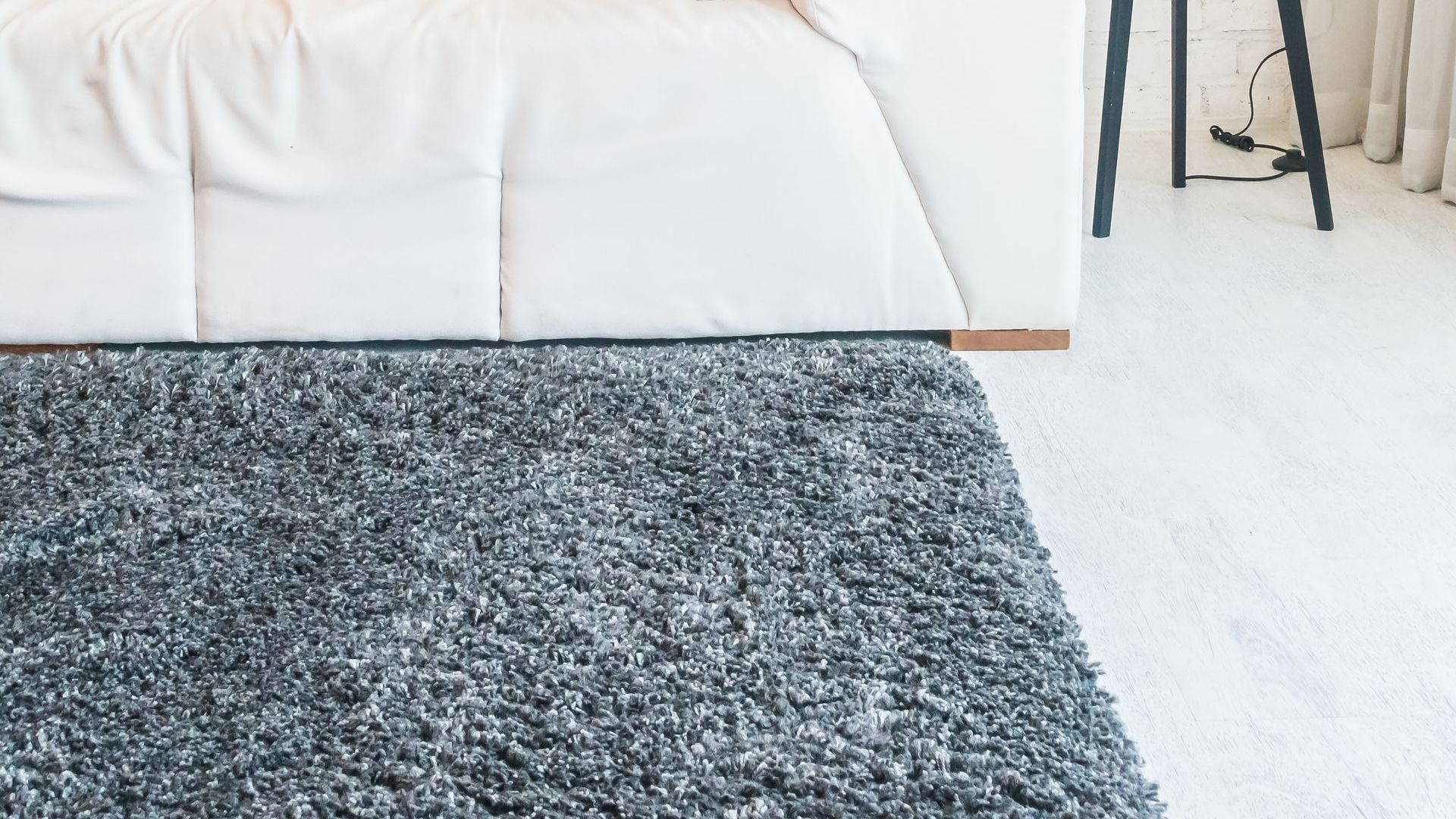 A white couch is sitting next to a gray rug in a living room.