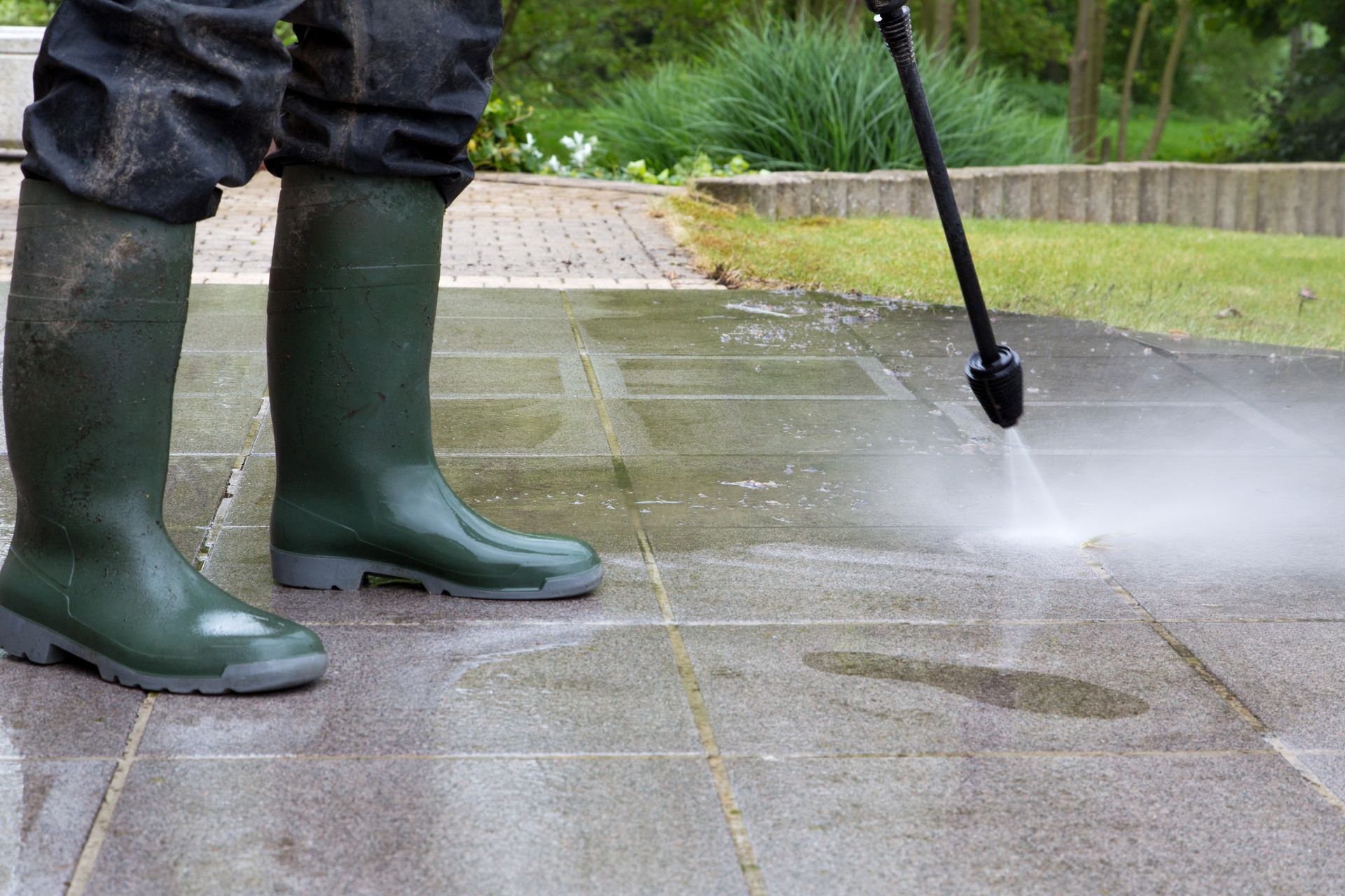 A person is using a high pressure washer to clean a patio.