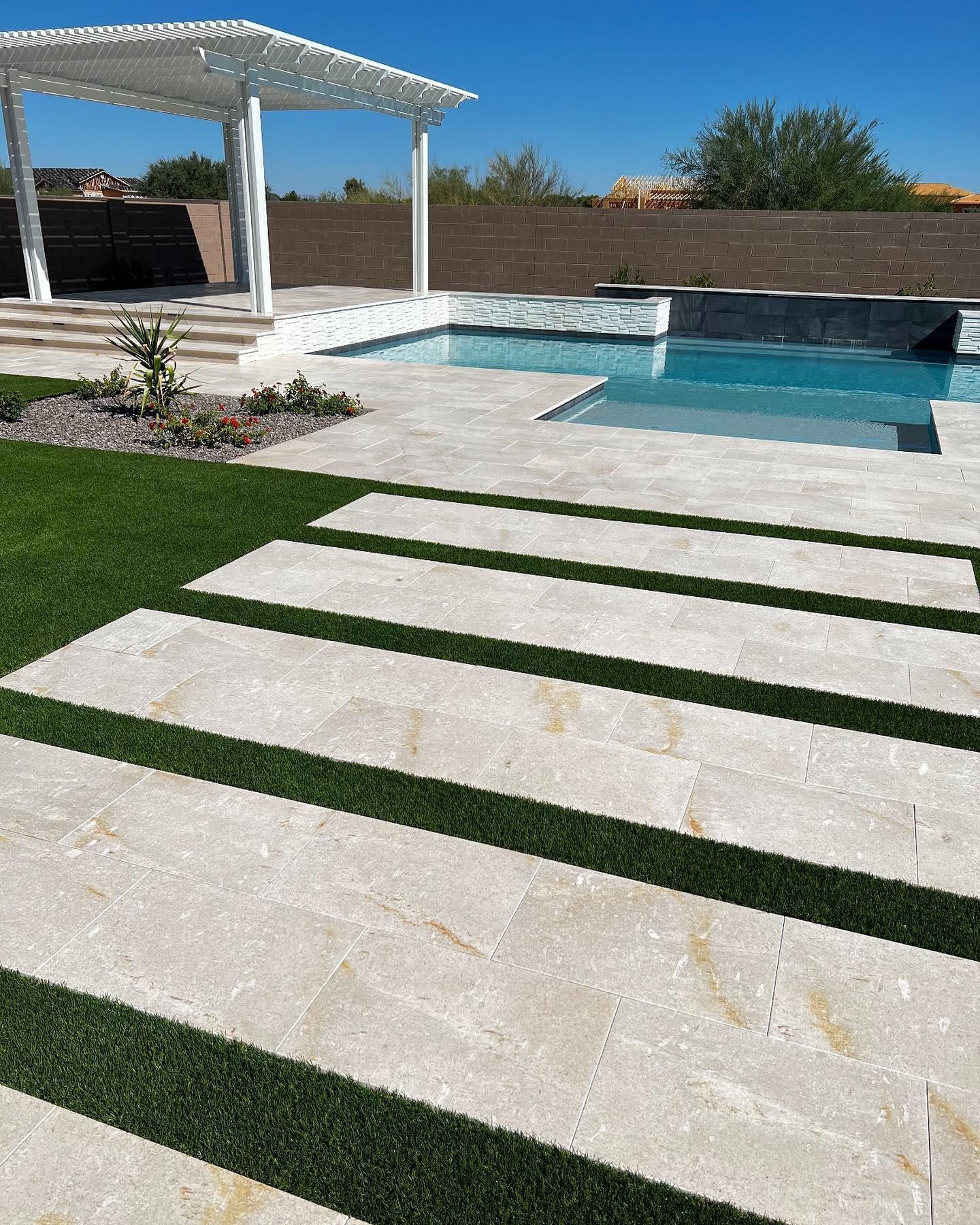 A swimming pool with a pergola and steps leading to it