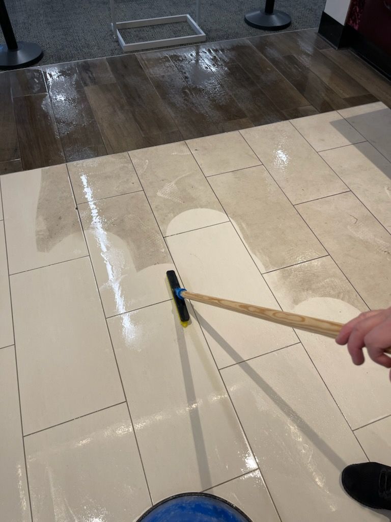 A person is cleaning a tiled floor with a broom