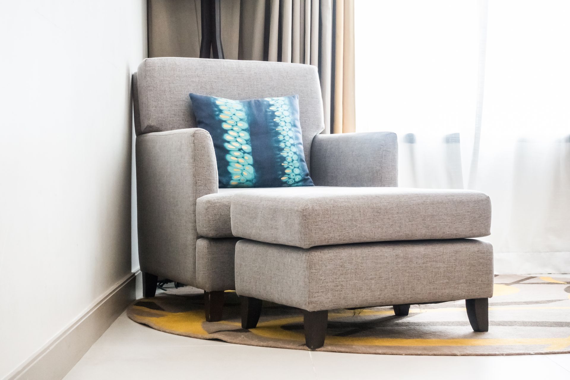 A chair and ottoman in a living room next to a window.