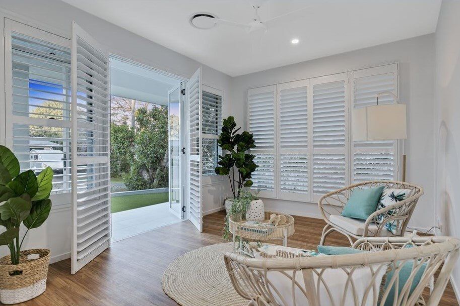 A Living Room With A Wicker Chair , Table And Shutters  — Norm Evans Floors Pty Ltd in Kunda Park, QLD