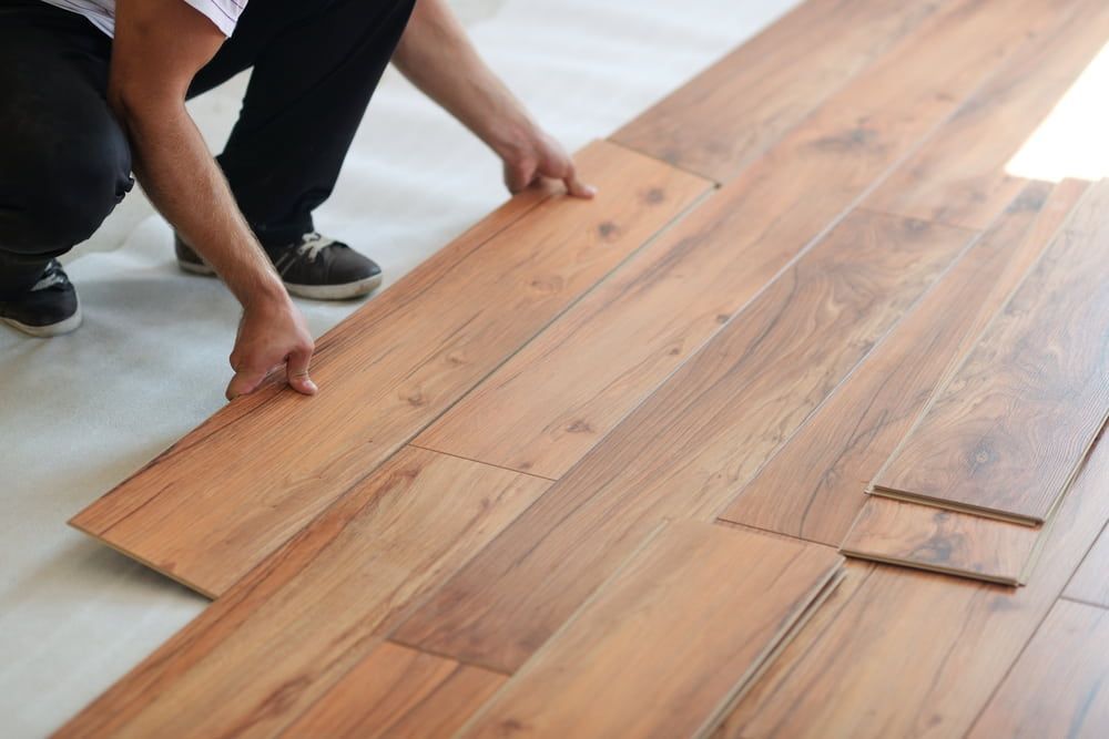 A Person Is Installing A Wooden Floor In A Room — Norm Evans Floors Pty Ltd in Nambour, QLD