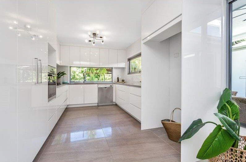 A Kitchen With White Cabinets And A Plant In The Corner  — Norm Evans Floors Pty Ltd in Kunda Park, QLD