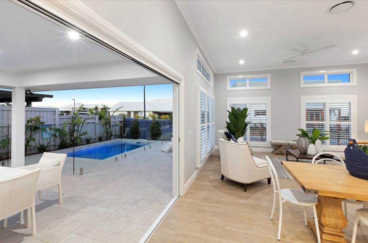 A Living Room With A Table And Chairs And A Swimming Pool In The Background — Norm Evans Floors Pty Ltd in Beerwah, QLD