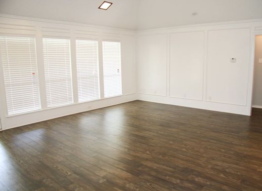 An Empty Living Room With Hardwood Floors And White Walls — Norm Evans Floors Pty Ltd in Kunda Park, QLD