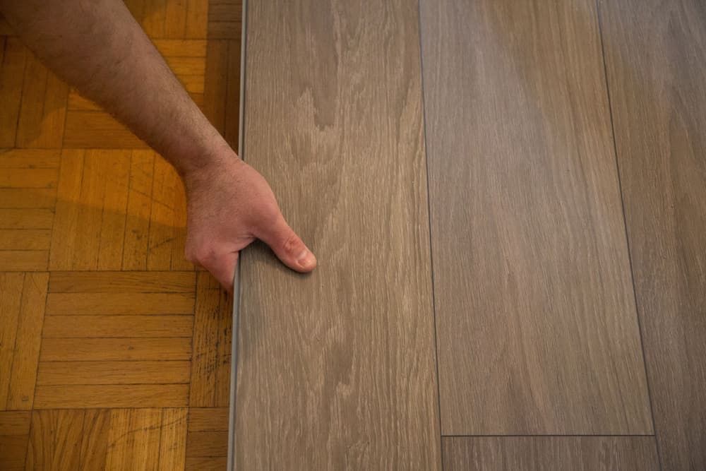 A Person Is Holding A Piece Of Wood On A Wooden Floor  — Norm Evans Floors Pty Ltd in Caloundra, QLD