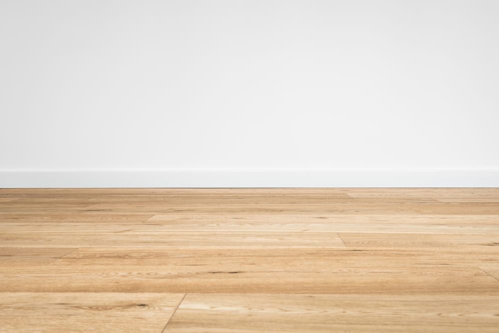 An Empty Room With A Wooden Floor And A White Wall — Norm Evans Floors Pty Ltd in Nambour, QLD