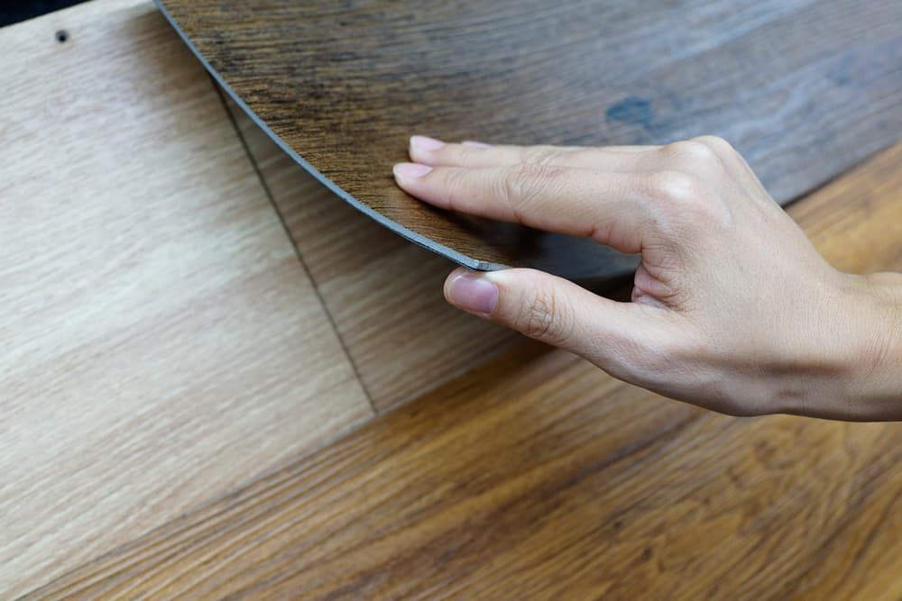 A Person Is Holding A Piece Of Wood In Their Hand — Norm Evans Floors Pty Ltd in Noosa, QLD