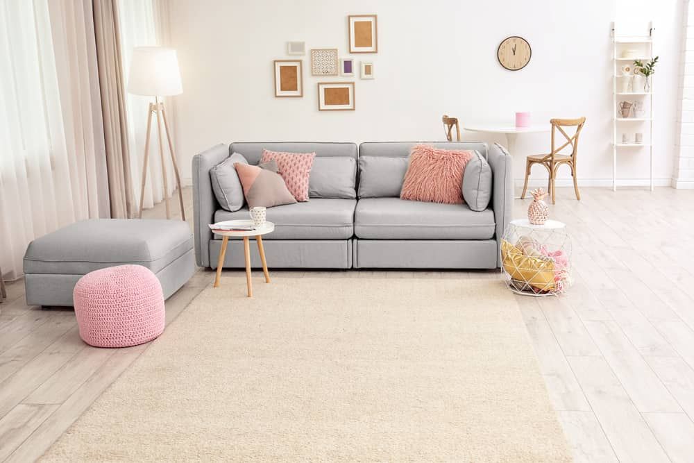 A Living Room With A Couch , Ottoman , Table And Rug — Norm Evans Floors Pty Ltd in Gympie, QLD