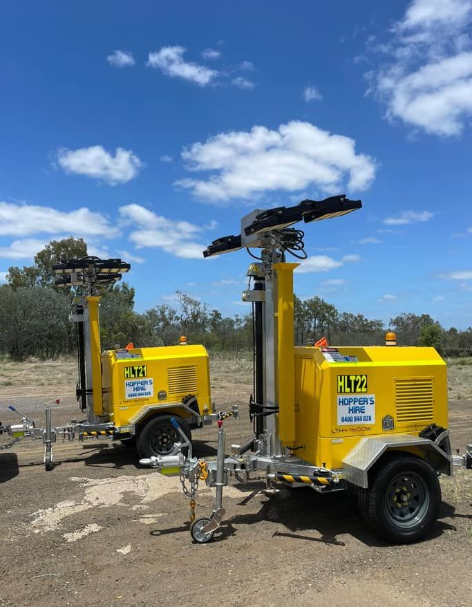 Two Yellow Trailers Are Parked Next To Each Other On A Dirt Road — Hybrid Power Australia In Blackwater, QLD