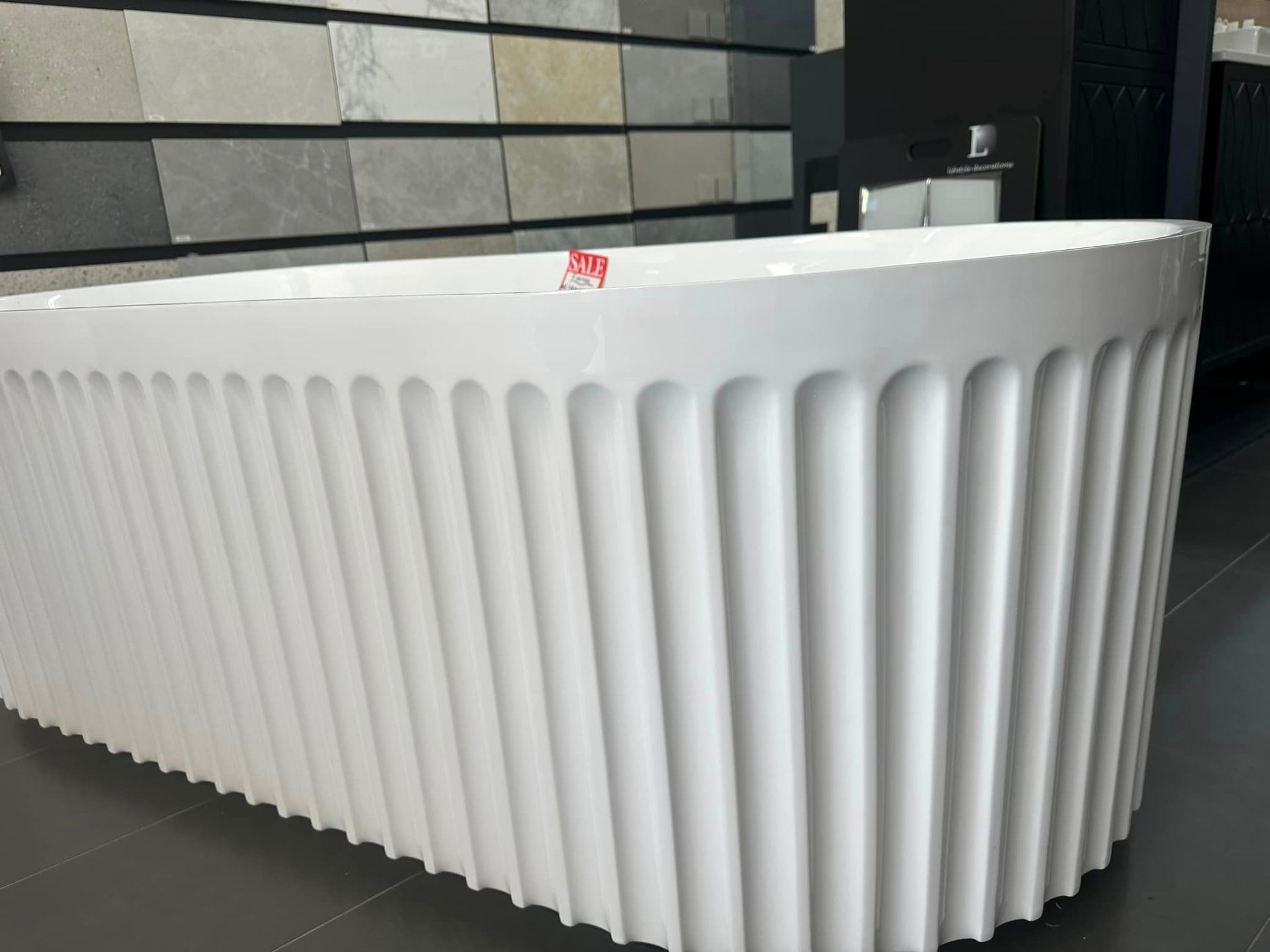 A White Bathtub With Vertical Ridged Exterior in Showroom Setting — Corrimal Discount Tiles and Bathroomwear in East Corrimal, NSW
