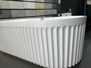 A White Bathtub With Vertical Ridged Exterior in Showroom Setting — Corrimal Discount Tiles and Bathroomwear in East Corrimal, NSW