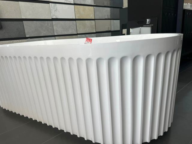 A White Bathtub With Vertical Ridged Exterior in Showroom Setting — Corrimal Discount Tiles and Bathroomwear in East Corrimal, NSW