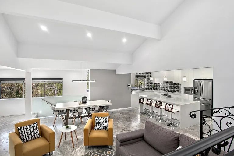Bright open-concept living space with kitchen, dining, and seating areas; featuring white walls, gold chairs, and marble floors — Corrimal Discount Tiles and Bathroomwear in East Corrimal, NSW