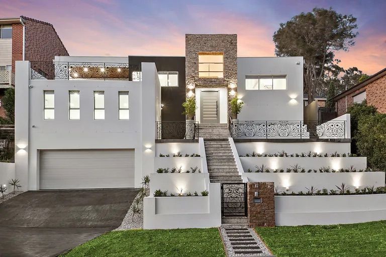 Modern white home with stone accents, tiered landscaping, and a long staircase leading to the entrance — Corrimal Discount Tiles and Bathroomwear in East Corrimal, NSW