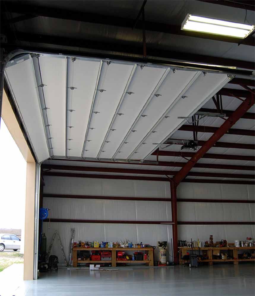 Open hangar door revealing interior with workbench and equipment.
